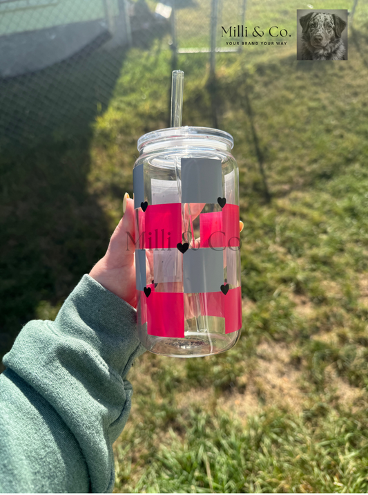 Clear water bottle with pink checkered design held by a person outdoors